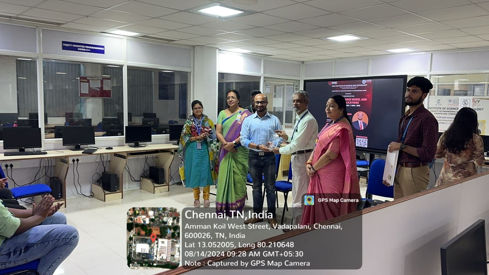 The guest speaker being presented with a memento in front of the workshop banner, faculty and students standing either side.